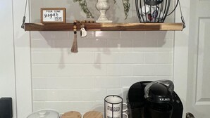 Une cuisine équipée d’une machine à café, de bocaux, d’un panneau et d’une plante suspendue.