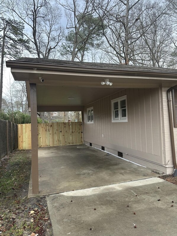 A single-story building with a covered patio area, a wooden fence, and a concrete driveway. - The Emerald Western Retreat at Durham (Durham)