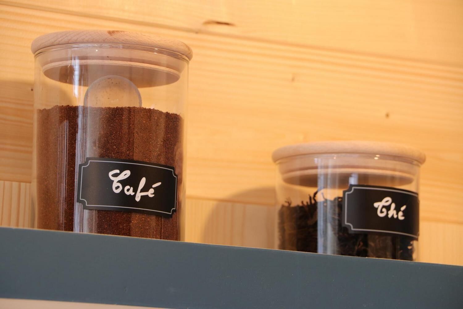 Two transparent containers with labels on a shelf.