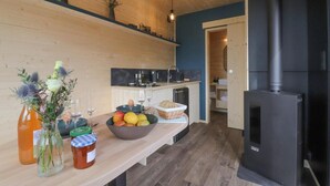 A modern kitchen with a wood stove, a fruit bowl, and a vase with flowers.