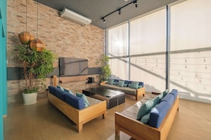 A modern living room with a brick wall, large windows, and a flat-screen TV. - 2Bed/2Bath, Pool, Gym & Mountain Views! (Monterrey)
