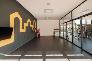 A modern gym with exercise equipment, a large mirror wall, and a black and yellow wall design.