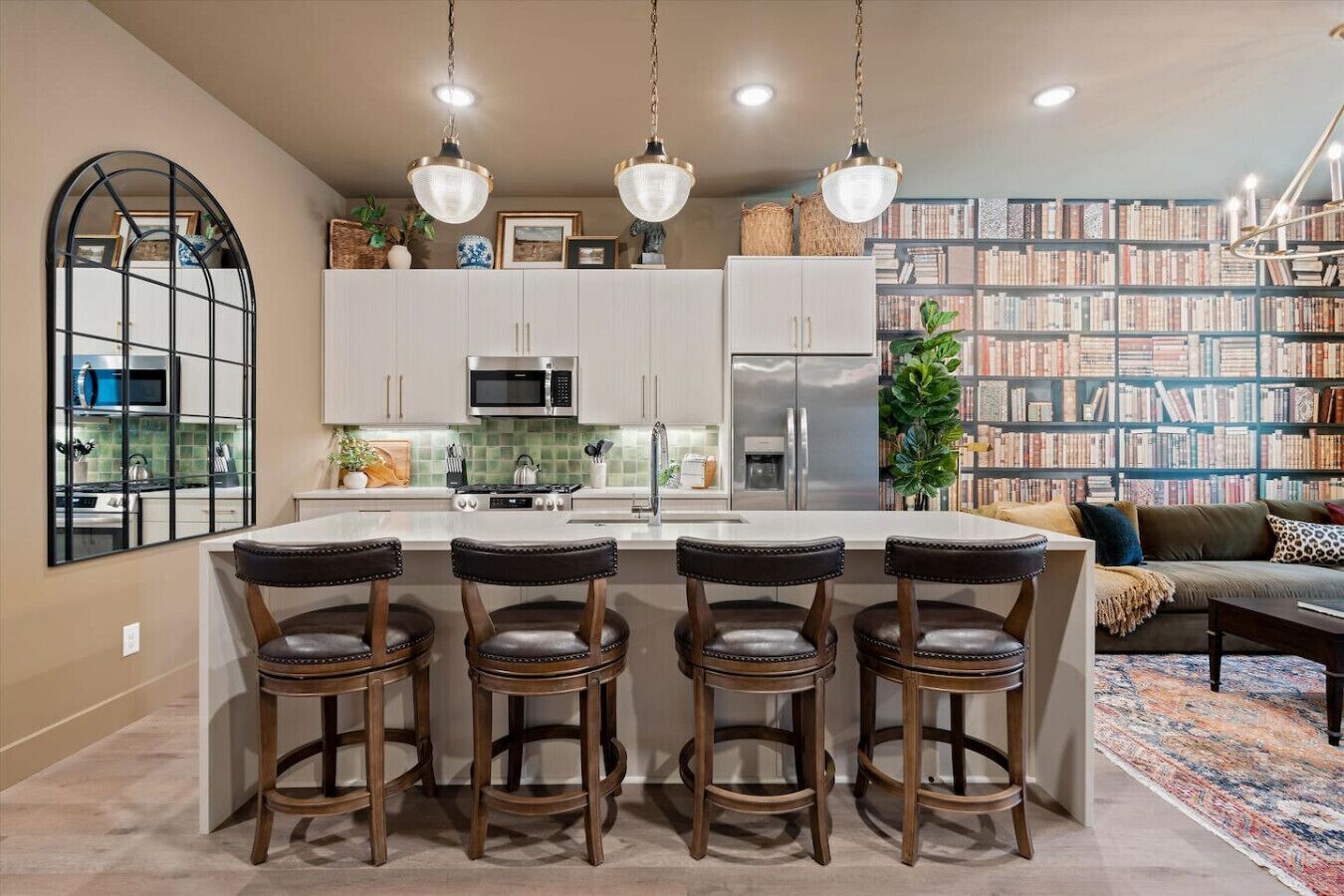 A kitchen with a central island, bar stools, a microwave, and a refrigerator.