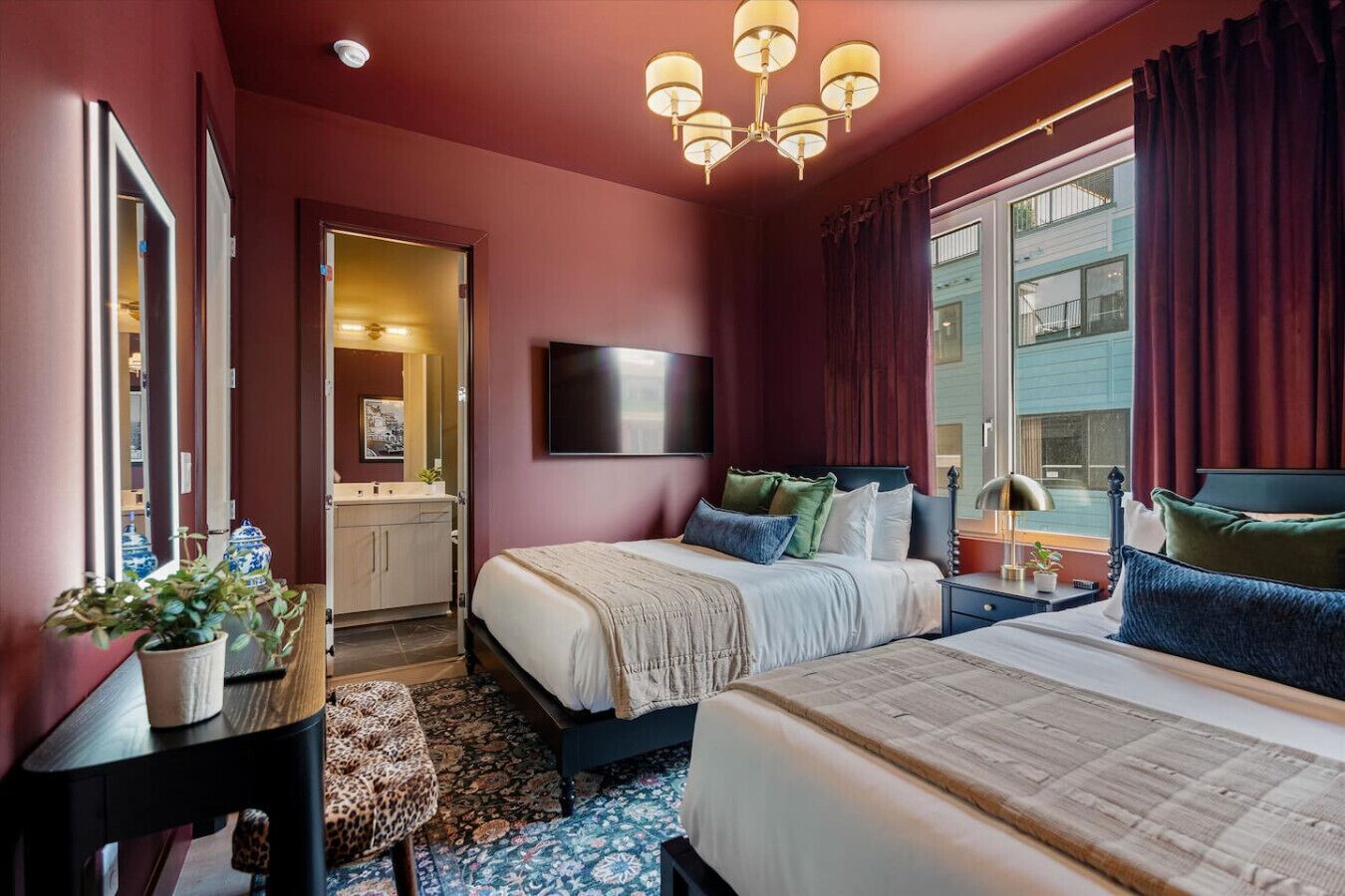 Une chambre d’hôtel avec deux lits, un grand miroir, un téléviseur à écran plat, une table de chevet avec une lampe et une vue sur l’extérieur.