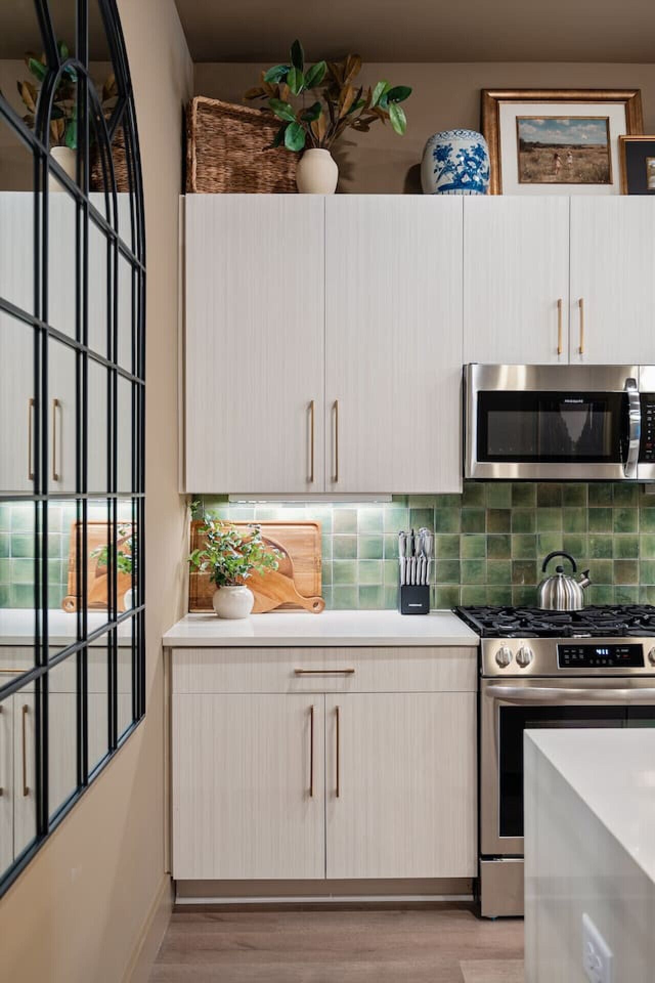 A modern kitchen with light-colored cabinets, a stainless steel microwave, and a gas stove.