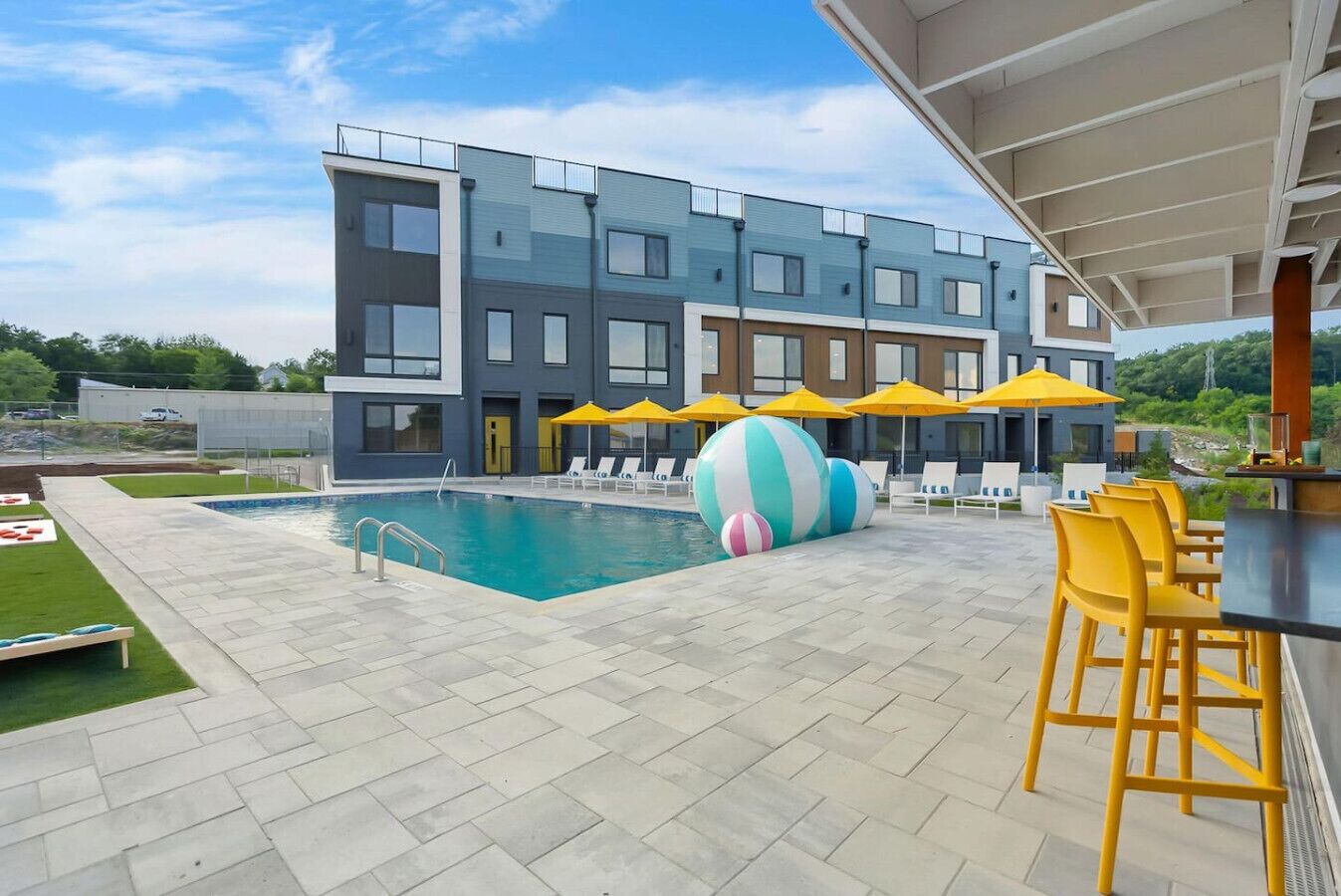 Un bâtiment moderne doté d’une piscine, d’un espace extérieur aménagé et de parasols.