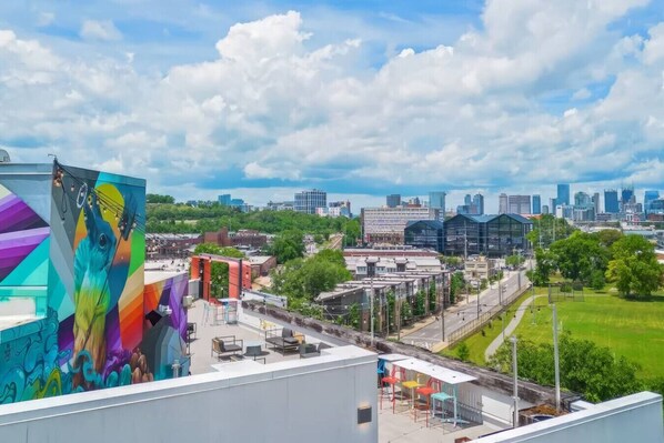 A cityscape with a prominent building featuring a colorful mural, a mix of modern and older architecture, and a clear view of the skyline.