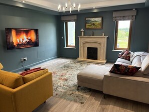 A living room with a fireplace, a television, and a sofa. - Home in Killarney - 6 Beds, Beautiful Home! (Killarney)
