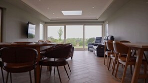 A spacious room with a dining area, a seating area with sofas, and a large window providing a view of the outdoors.