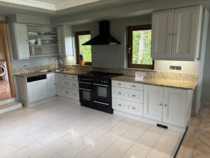 Una cocina con armarios blancos, una estufa negra y una ventana.