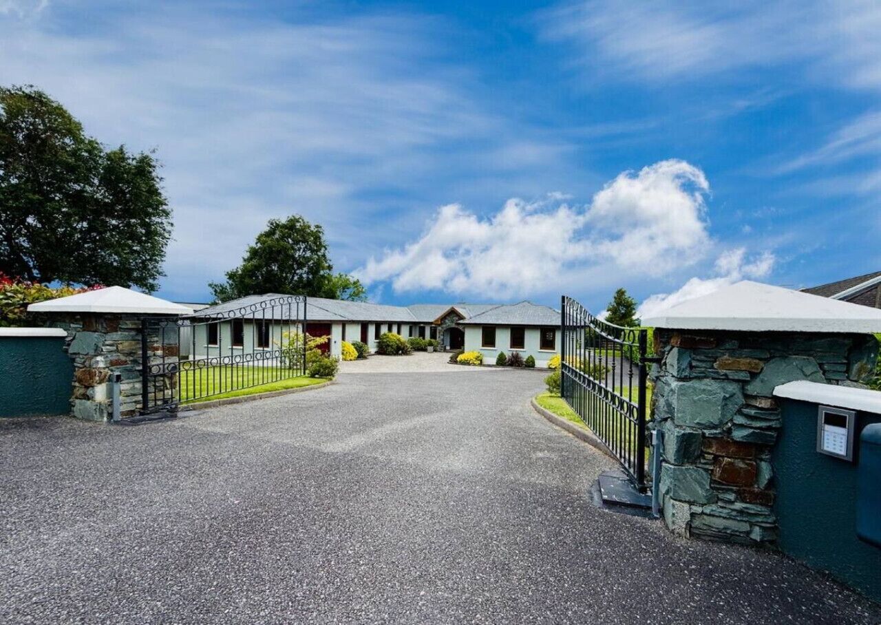 A building with a gravel driveway, stone walls, and a metal gate.
