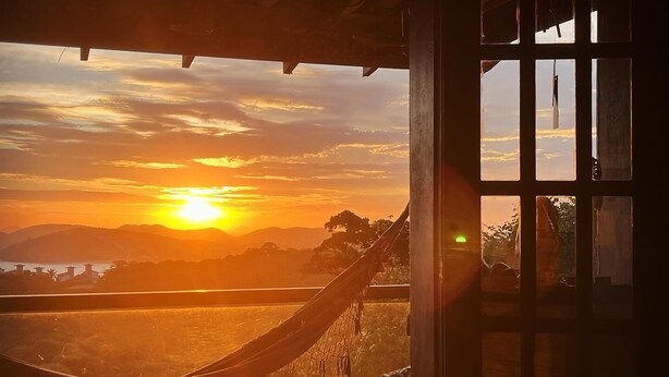 Eine Hängematte auf einer Veranda mit Blick auf den Sonnenuntergang.