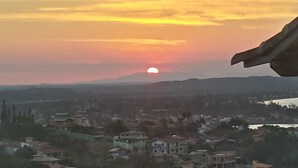 Ein Sonnenuntergang über einer Stadt mit Gebäuden und Hügeln im Hintergrund.