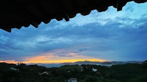 Eine Landschaftsansicht mit Sonnenuntergang, Bergen und verstreuten Gebäuden.
