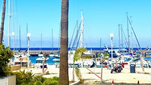 Ein Hafen mit vertäuten Booten, Palmen und blauem Himmel.