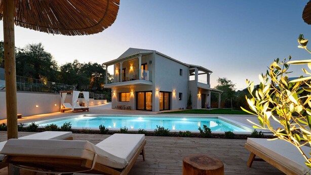 Una casa moderna de dos pisos con piscina, sillas de descanso y terraza de madera.