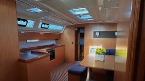 Een kleine kombuis met kitchenette, een eethoek met tafel en bank, en dakramen.