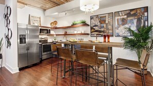 Una cucina moderna con soffitto in legno, elettrodomestici in acciaio inossidabile e un angolo bar con sgabelli.