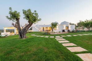 Une maison moderne à l’extérieur blanc, avec un chemin de pierre menant à l’entrée et une pelouse bien entretenue.