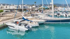 A marina with boats docked, a clear sky, and buildings in the background.