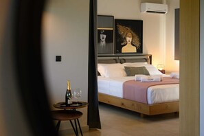 Ein Schlafzimmer mit einem Bett, einem Nachttisch mit Flasche und Glas sowie zwei gerahmten Kunstwerken an der Wand.
