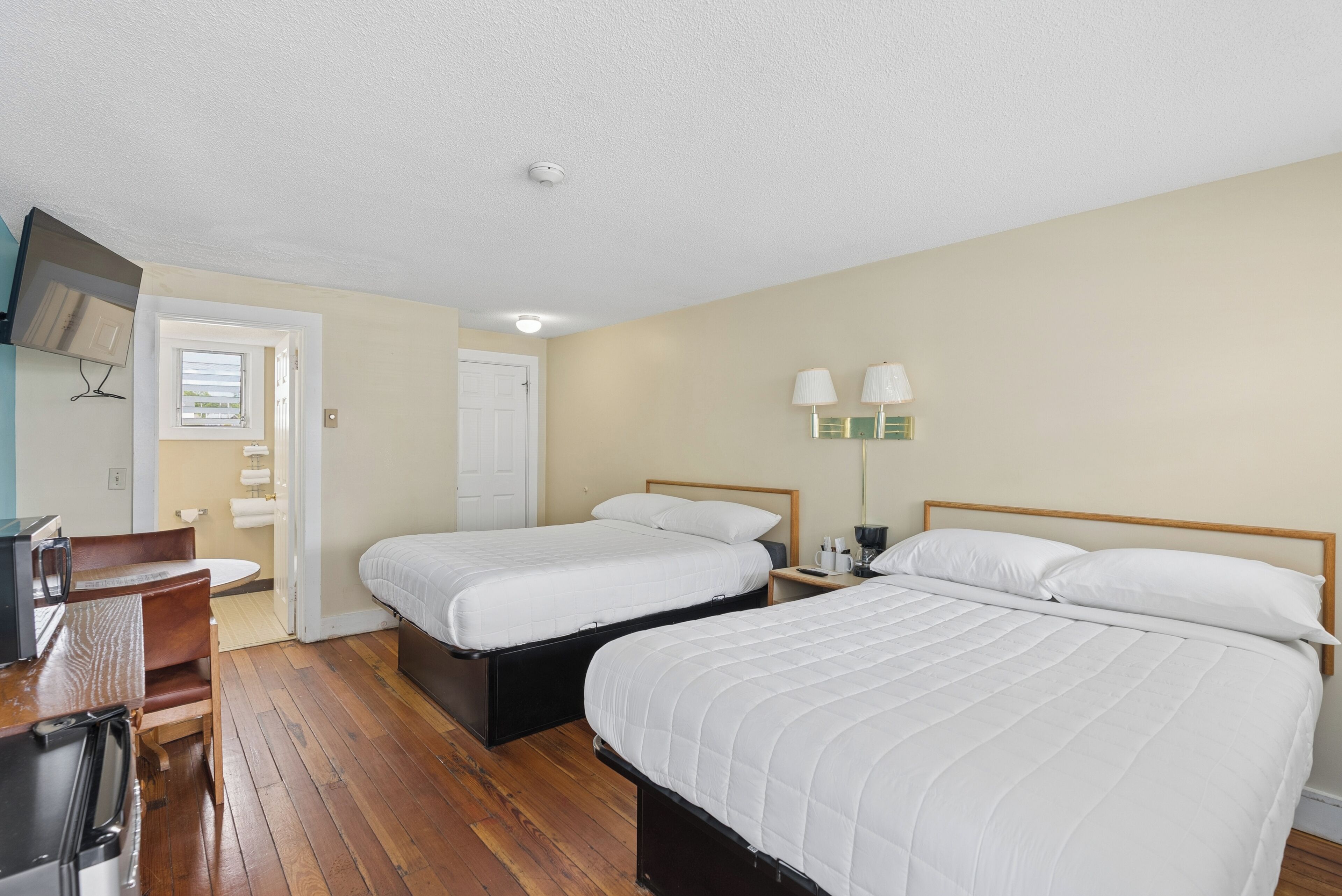 A bedroom with two beds, a desk, and a chair.