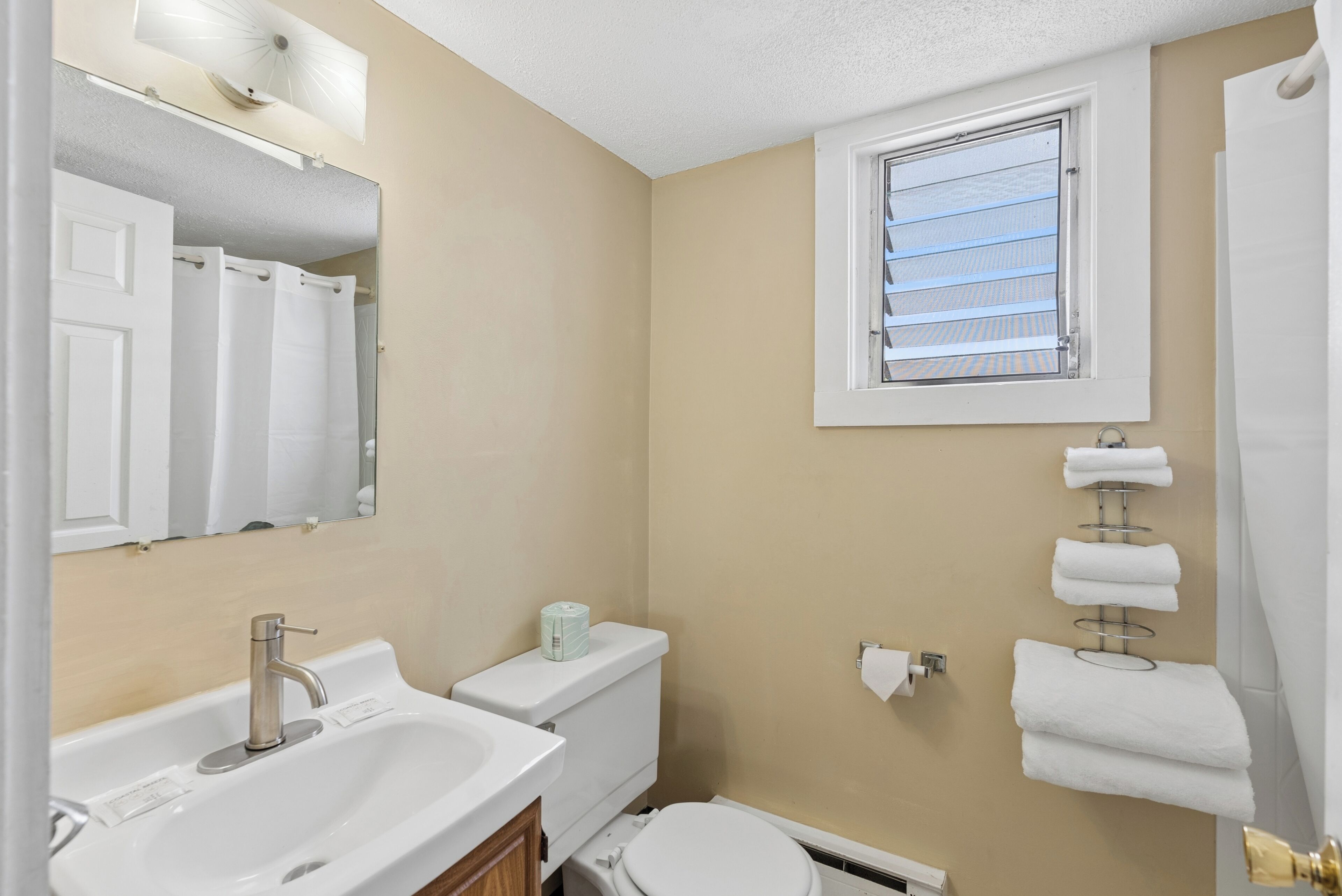 A bathroom with a sink, toilet, and a window with blinds.