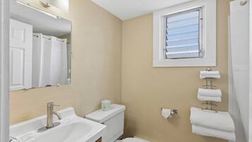A bathroom with a sink, toilet, and a window with blinds.