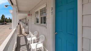 A building with a blue door, white walls, and a covered porch with white chairs. - The Inn at SOHO Square (Old Orchard Beach)