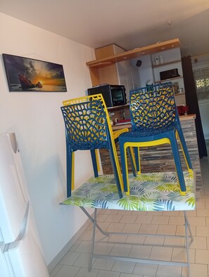 A dining area with two chairs, a table, a television, and a kitchen in the background. - Apartment 500m from the sea and 2min from Etel! (Erdeven)