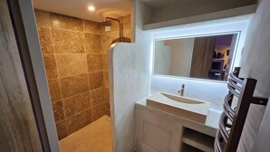 Een badkamer met een douche, een wastafel en een spiegel.