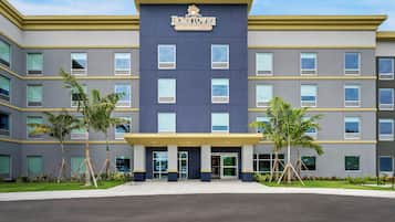 A multi-story building with a sign reading 'HomeTown Studios.' It features a modern architectural design with a flat roof, large windows, and a flat entrance.