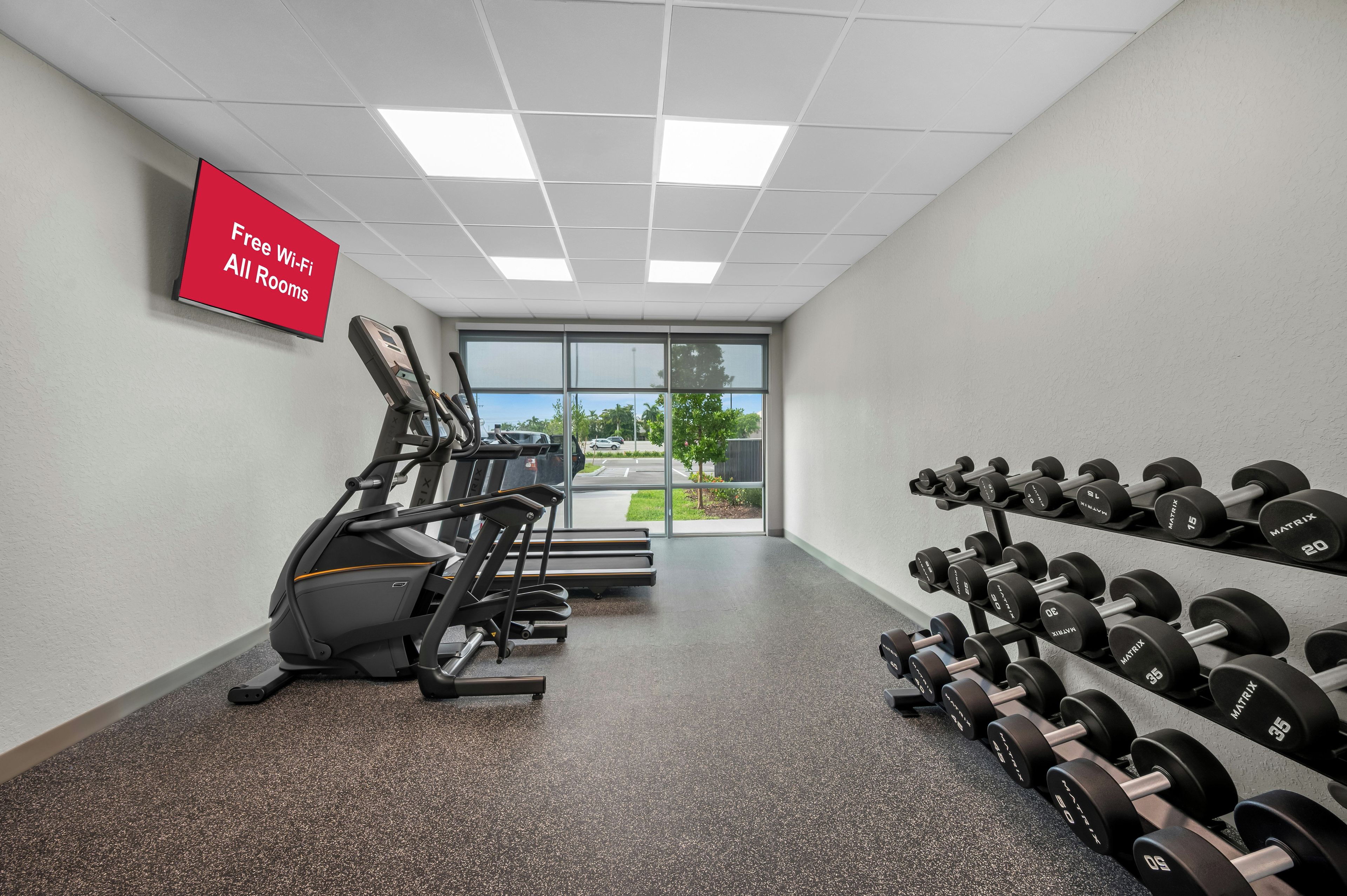 Una palestra con tapis roulant, pesi e un cartello che indica Wi-Fi gratuito in tutte le camere.