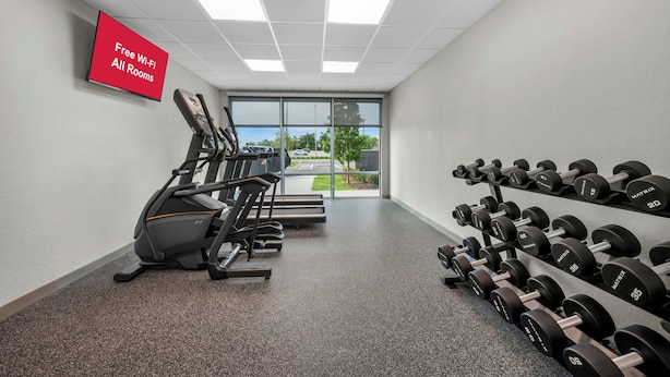 A gym with treadmills, dumbbells, and a sign indicating free Wi-Fi in all rooms. - HomeTowne Studios by Red Roof Fort Myers (Fort Myers)