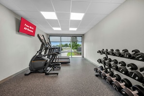 A gym with treadmills, dumbbells, and a sign indicating free Wi-Fi in all rooms.