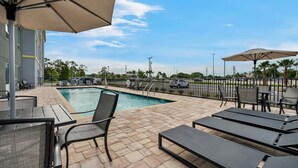 A poolside area with lounge chairs, umbrellas, and a view of the surrounding landscape.