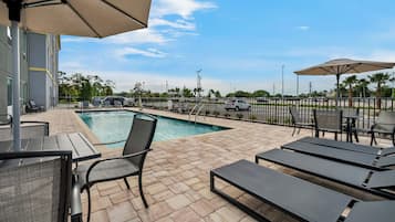 A poolside area with lounge chairs, umbrellas, and a view of the surrounding landscape.