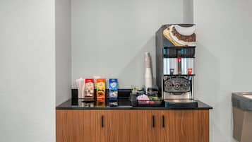 Een koffieapparaat, wegwerpbekers en koffiekapsules op een aanrecht.