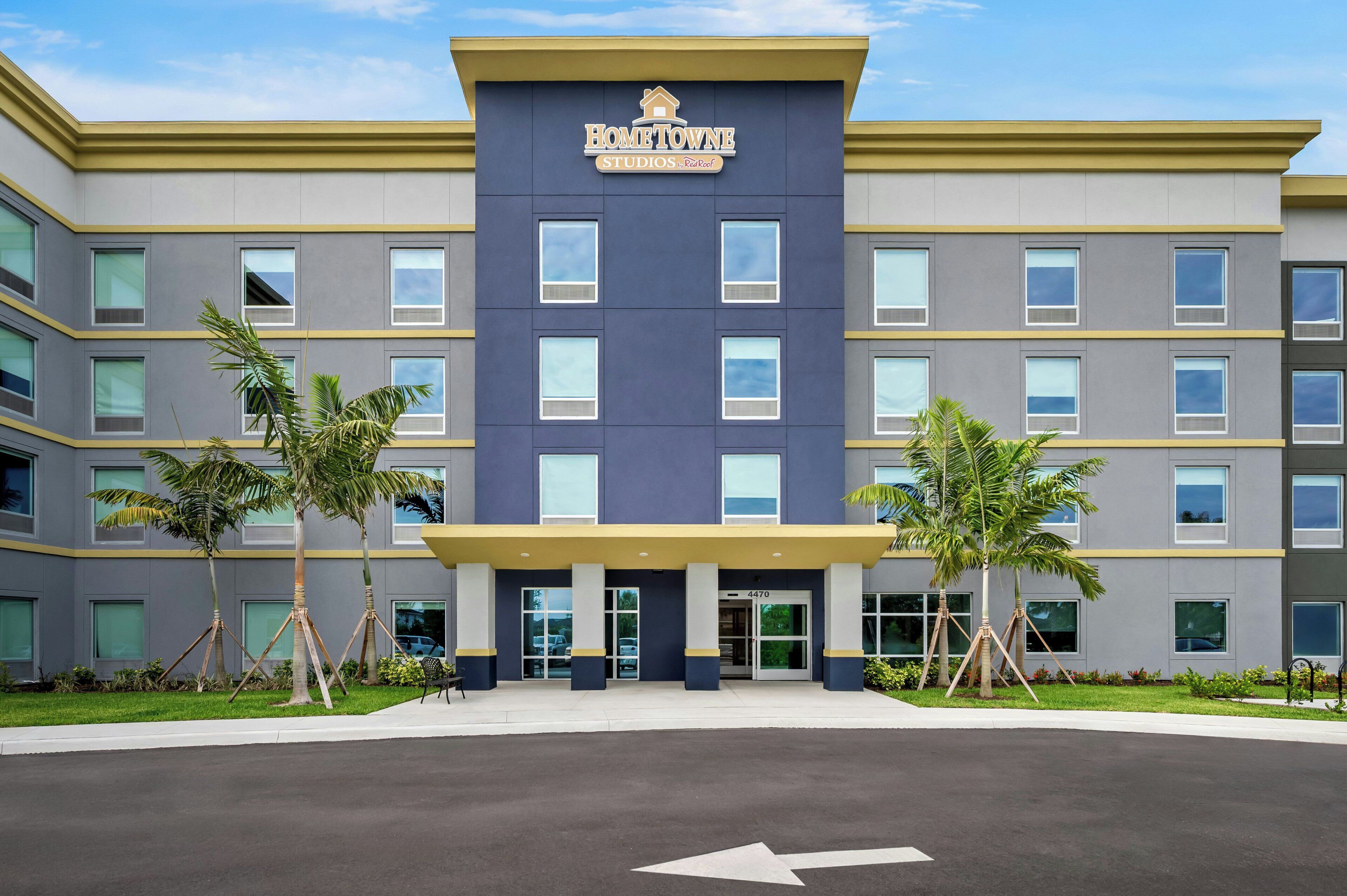 A multi-story building with a sign reading 'HomeTown Studios.' It features a modern architectural design with a flat roof, large windows, and a flat entrance.