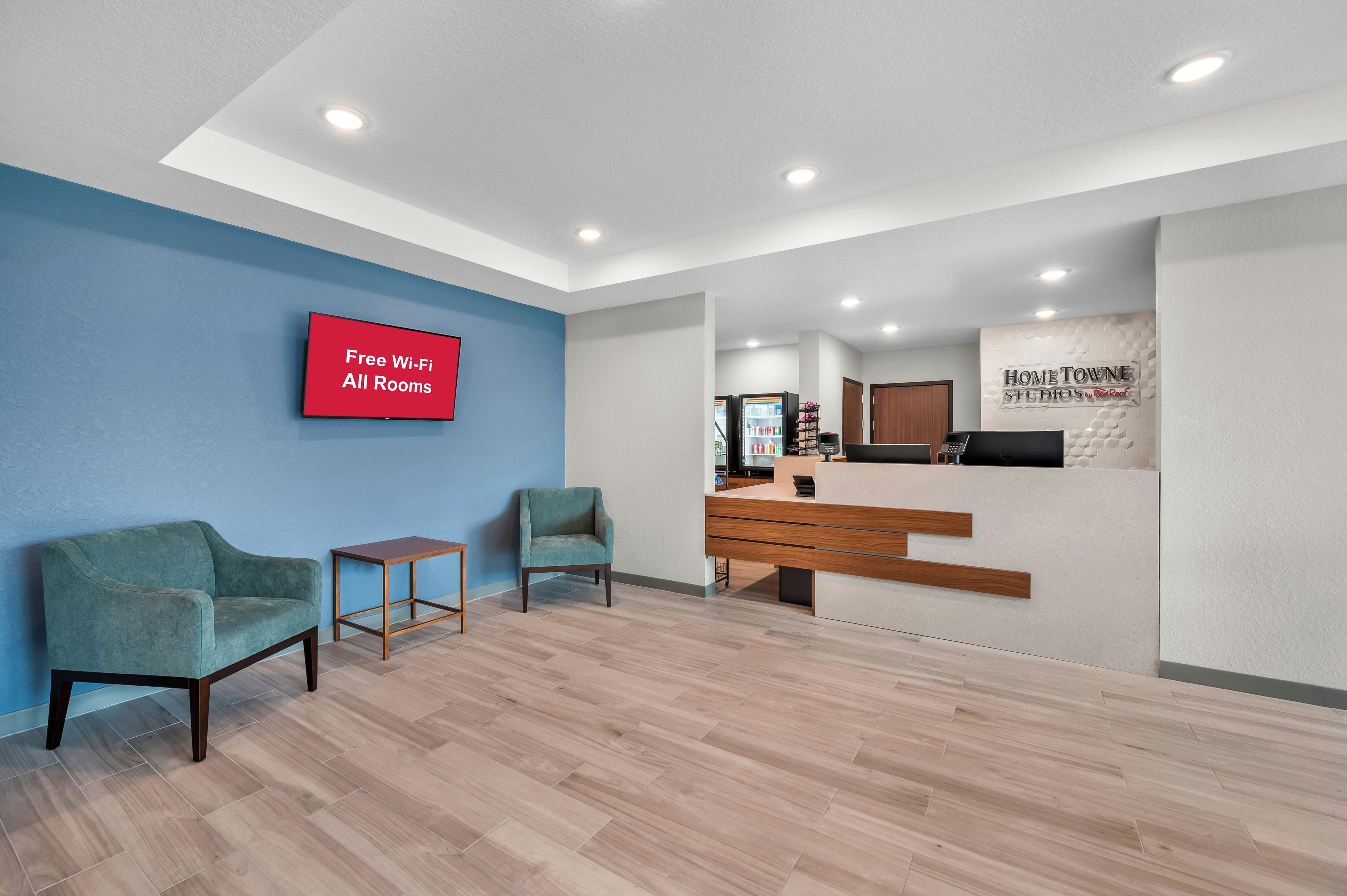 A reception area with a 'Free Wi-Fi All Rooms' sign, a reception desk, and a blue wall.