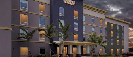 A modern hotel building with a flat roof, multiple windows, and a sign reading 'HOMETOWNNE STUDIOS.'