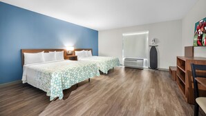 A hotel room with two beds, a desk, a chair, a TV, and a window. - HomeTowne Studios by Red Roof Fort Myers (Fort Myers)