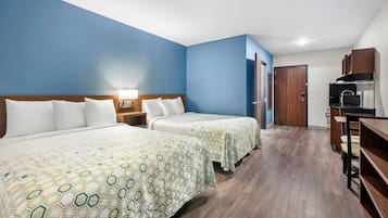Habitación de hotel con dos camas, un escritorio, microondas y armario.