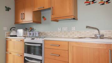A kitchen with wooden cabinets, a built-in oven, a toaster, and a sink.