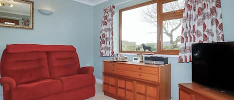 A living room with a red sofa, wooden cabinet, and a television.
