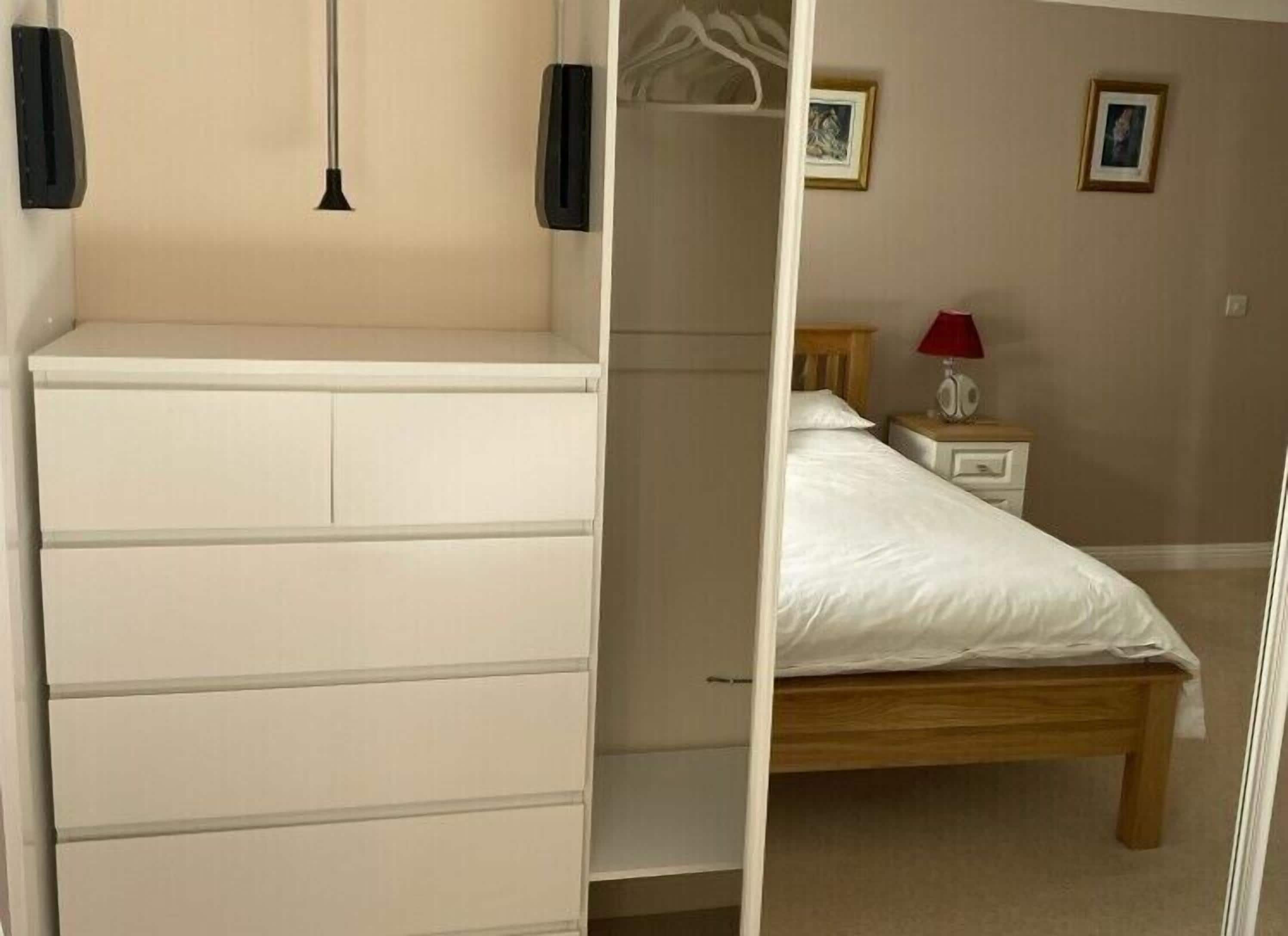 Ein Schlafzimmer mit einem Bett, einem Nachttisch, einer Kommode und einer Hängeleuchte.