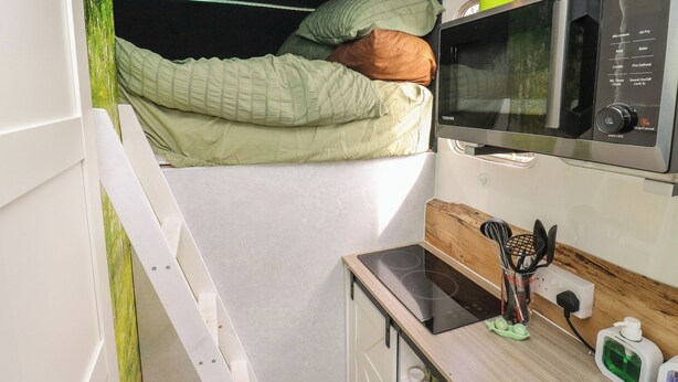 A compact kitchenette with a microwave, a small stove, and a shelf with containers labeled 'Sugar' and 'Coffee'. - The Horse Box (Blaydon on Tyne)