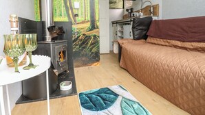 A cozy room with a bed, a table with glasses, a fireplace, and a forest mural. - The Horse Box (Blaydon on Tyne)