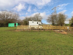 A white RV with a horse symbol, a green shed, and a wooden fence in a grassy field. - The Horse Box (Blaydon on Tyne)