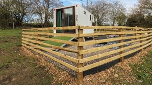 A small, single-story structure with a door and windows, surrounded by a wooden fence. - The Horse Box (Blaydon on Tyne)